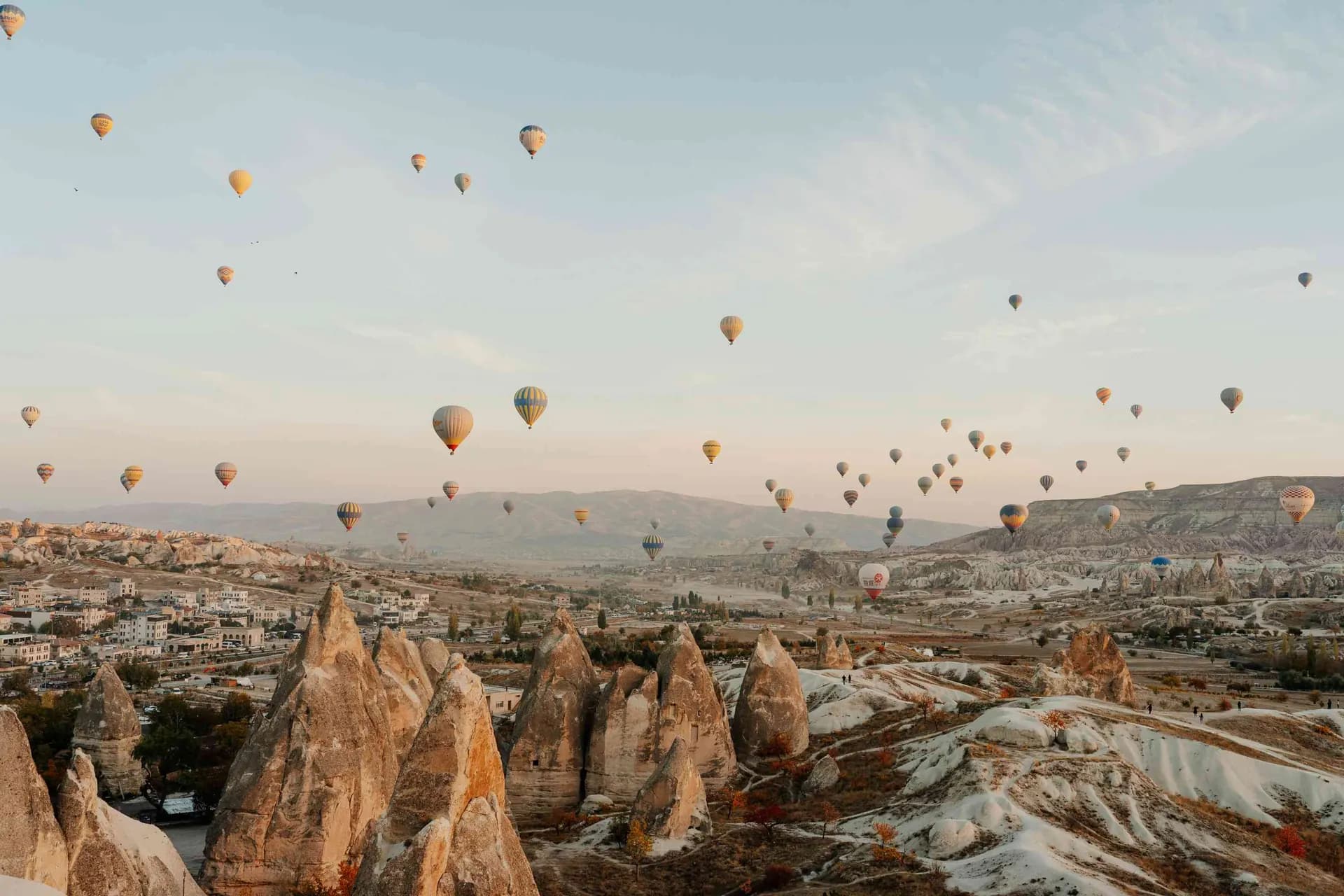 Dozens of hot air balloons drifting over the fairy chimneys of Cappadocia at sunrise on a luxury Turkey tour